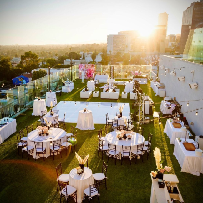Wedding reception on the roof, artificial grass, round tables, dance floor, string lights, 