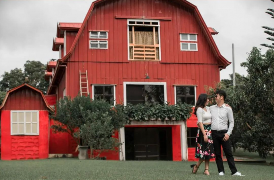 A couple in front or classic red American barn