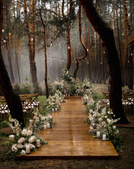Wooden path in the forest, decorated with white flowers and greenery, wooden chairs, string lights