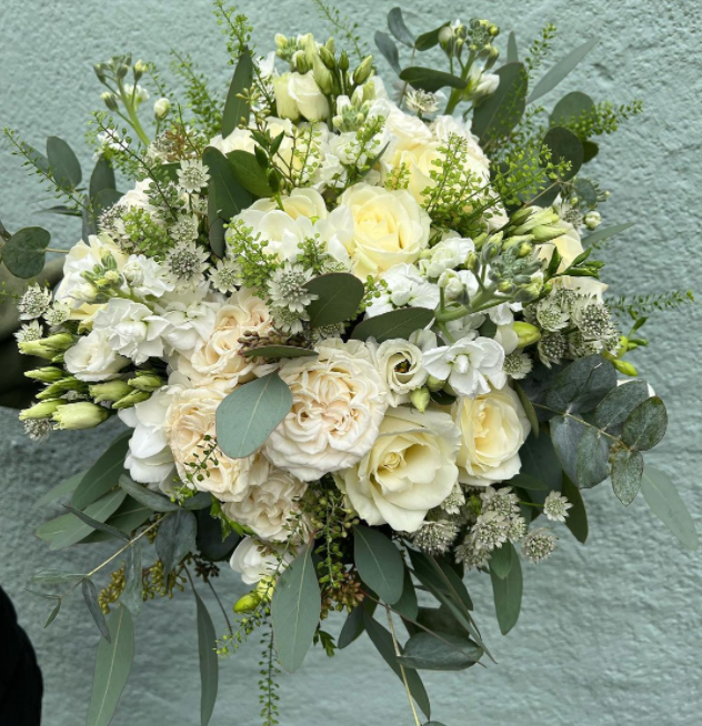 Bridal bouquet with white roses, dark greenery, Preria roses and peonies