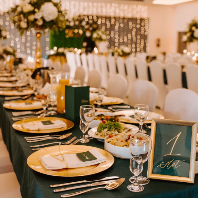 Dark green table cloths, golden plates and simple glasses and utensils. Golden warm light in the background