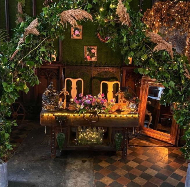 Sweetheart table hidden under the leaves, mirror on the floor, old wood, violet flowers and subtle lights