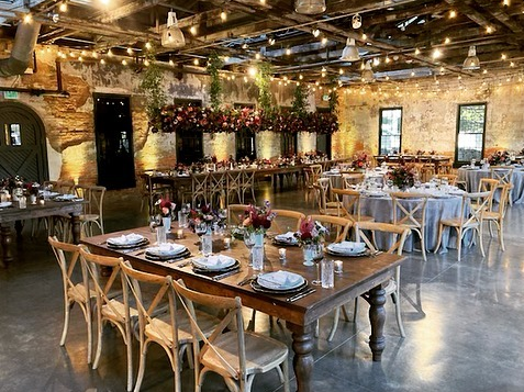 Industrial wedding venue with light bulb lighting, antique table with simple wooden chairs