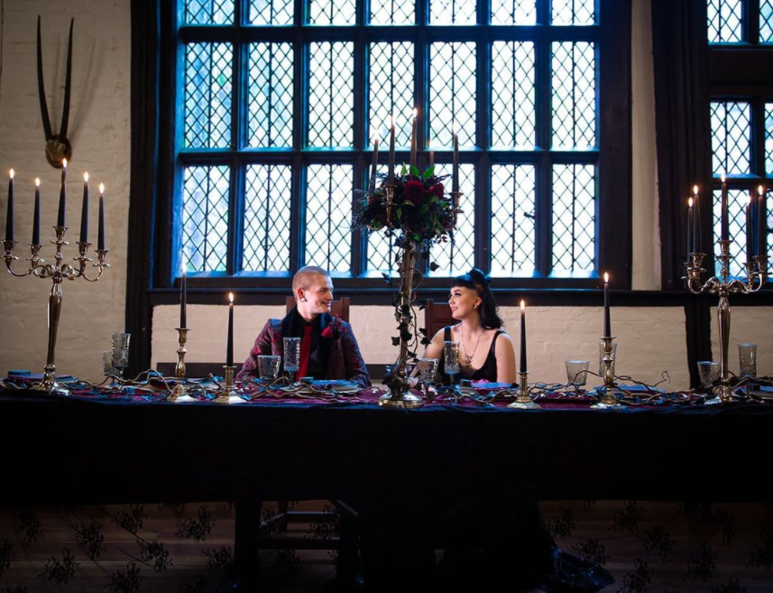 Castle interior with big windows, black table cloths, long black candles, high candelabras and candleholders