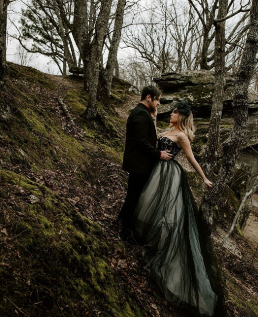 Photoshoot photo in the rocky forest with mossy stones, white dress with black tulle, black hairband